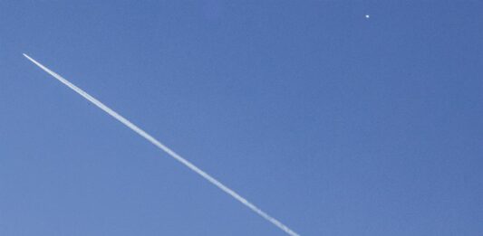 Un avión comercial (i) vuela por debajo del globo espía chino