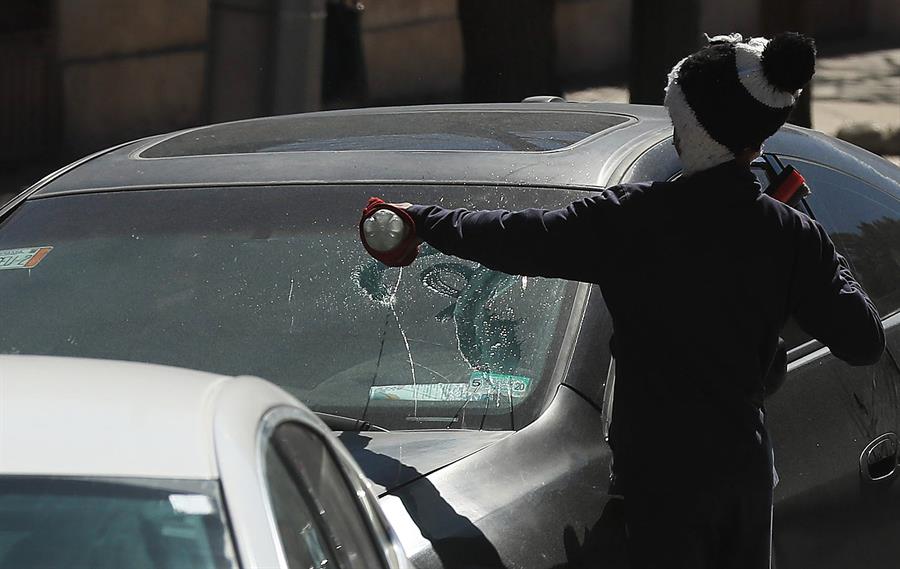 Un migrante limpia un carro