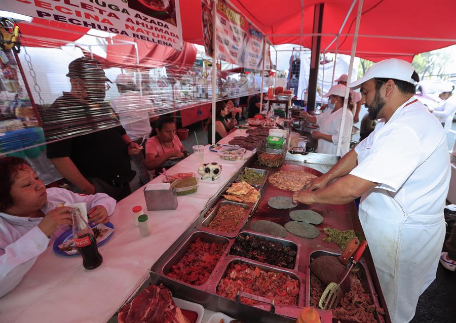 Una persona atiende a clientes en un puesto de tacos
