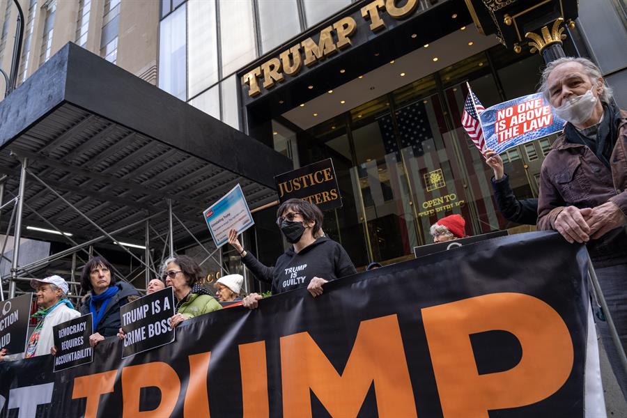 Unas personas sostienen pancartas en contra del expresidente Donald Trump (2)