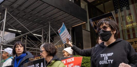 Unas personas sostienen pancartas en contra del expresidente Donald Trump (4)