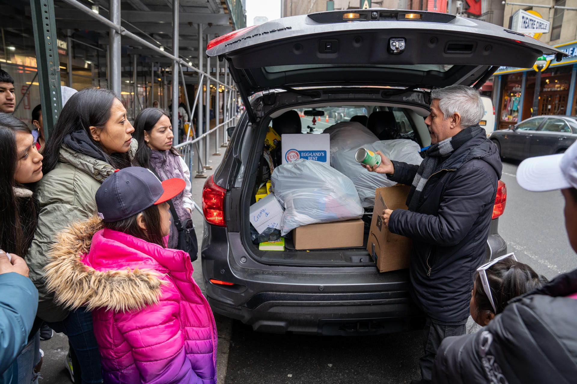 El sacerdote luterano y activista Fabi&aacute;n Arias (d), de la iglesia San Pedro en Manhattan, reparte ropa y alimentos enlatados a unos inmigrantes frente al hotel donde residen en el barrio de Manhattan en Nueva York.