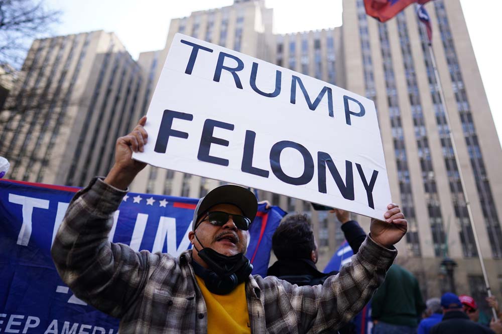 Un manifestante sostiene una pancarta en la que se puede leer "Trump delito" frente a los juzgados de Nueva York este martes.