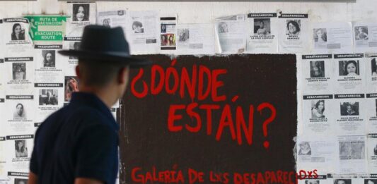 Un hombre observa un mural con fichas de personas desaparecidas