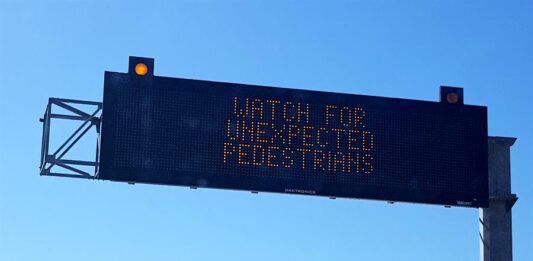 panel digital que advierte a los conductores tener cuidado con posible peatones inesperados