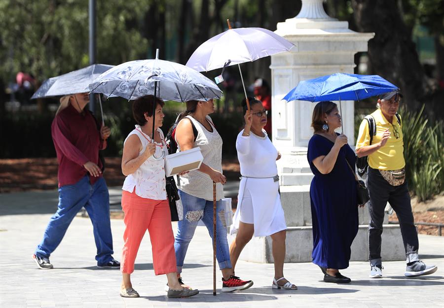Personas se protegen del sol con sombrillas Personas se protegen del sol con sombrillas