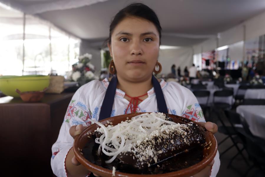 Una cocinera sirve un plato de enchiladas con mole durante la feria del típico platillo (2)