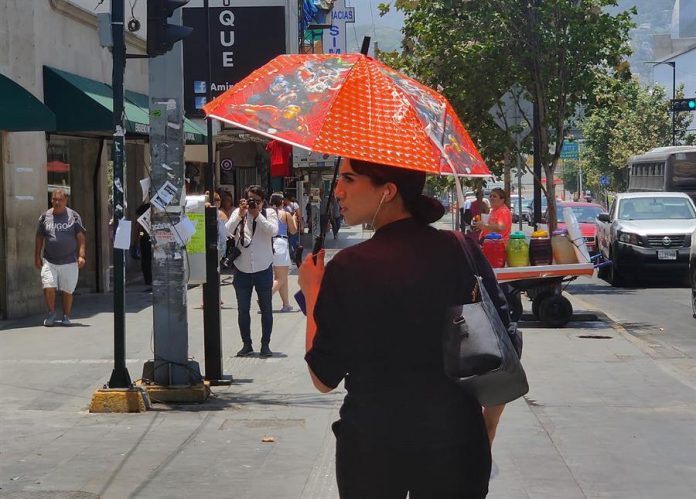 Una mujer se protege del sol con una sombrilla hoy, en la ciudad de Monterrey