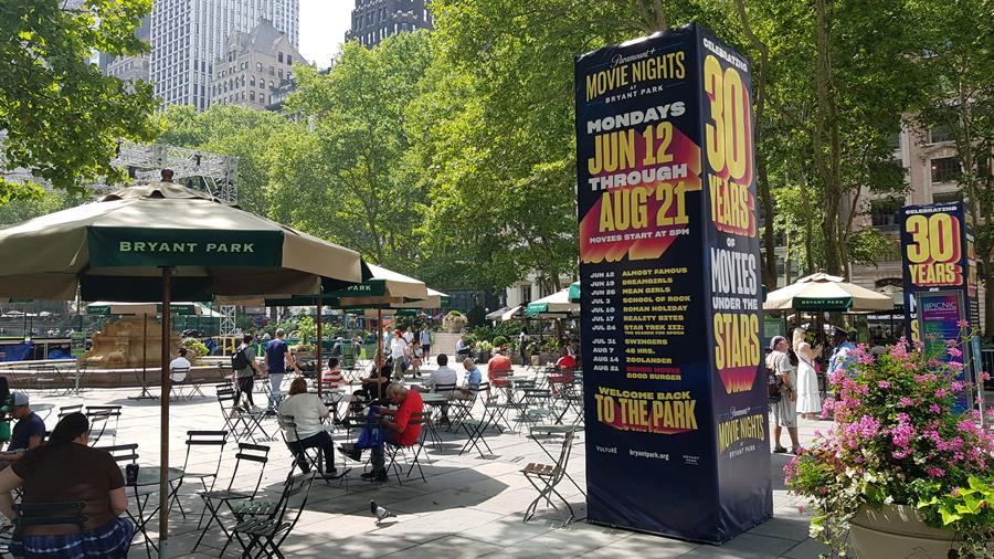 Unas personas descansan junto a un cartel del ciclo Movies under the stars