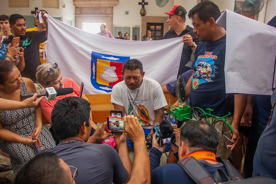 El peregrino David González (c) habla con la prensa luego de llegar en bicicleta con una imagen de la Virgen de Guadalupe