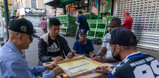 Un grupo de personas juega dominó en la calle 190 de St. Nicholas, un sector conocido como la Pequeña Dominicana