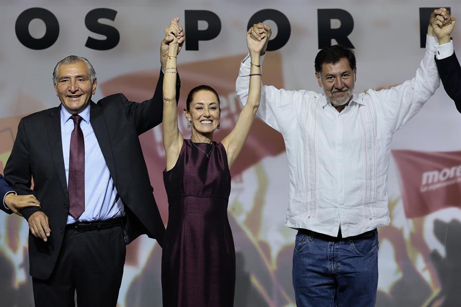 Adán Augusto López (i) y el diputado por el Partido del Trabajo Gerardo Fernández Noroña (d) levantan la manos a la exjefa de Gobierno de Ciudad de México, Claudia Sheinbaum Sheinbaum