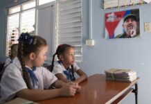 Dos niñas asisten a las aulas junto a una foto de Fidel Castro