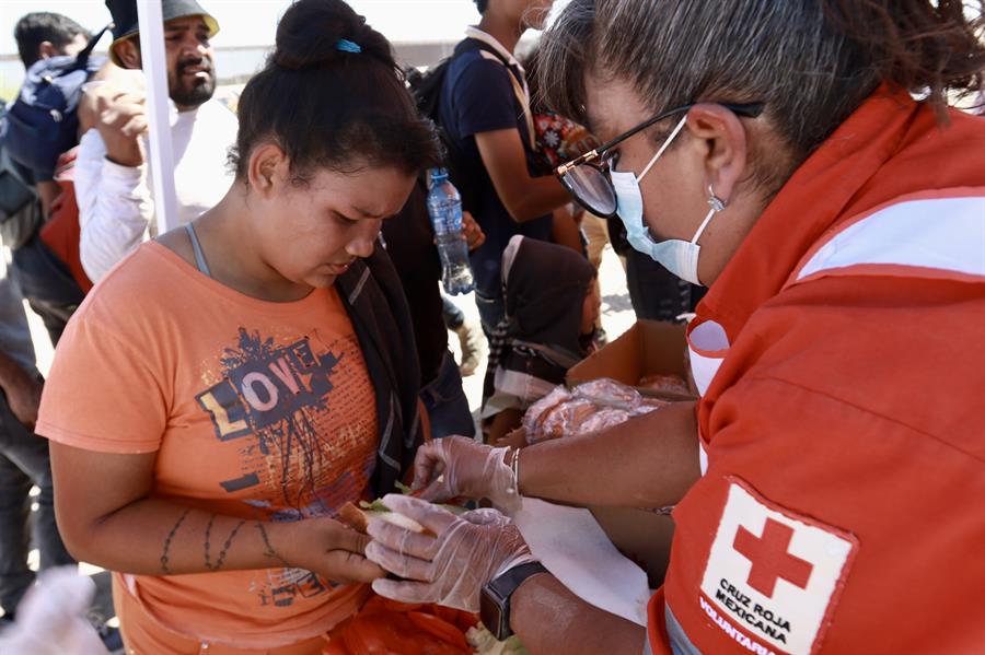 Una voluntaria de la Cruz Roja reparte alimentos a migrantes hoy, en Ciudad Ju&aacute;rez (3)
