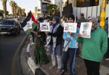 manifestantes sostienen banderas y pancartas en una protesta en Johannesburgo organizada por el grupo Judíos sudafricanos por una Palestina libre