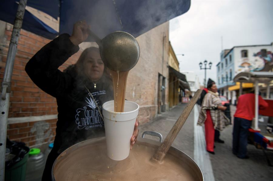 Una comerciante ambulante vende atole (dulce de ma&iacute;z en agua) debido al descenso de la temperatura