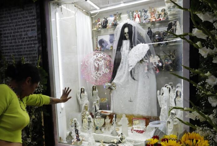 Una mujer reza hoy ante la Santa Muerte durante la conmemoración del XXII aniversario de su altar en el popular barrio de Tepito