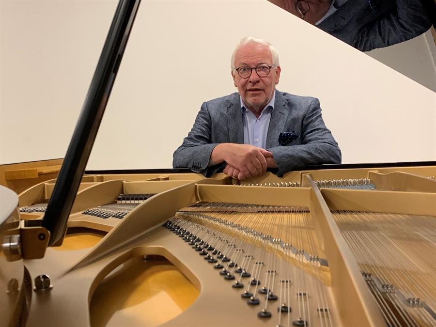 Chris Maene mientras posa junto al piano curvo ideado por el arquitecto uruguayo Rafael Vi&ntilde;oly