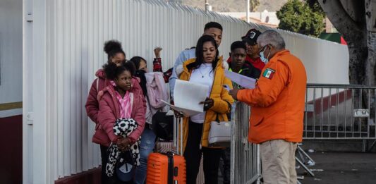 Migrantes hacen fila para solicitar un proceso de asilo en Estados Unidos.