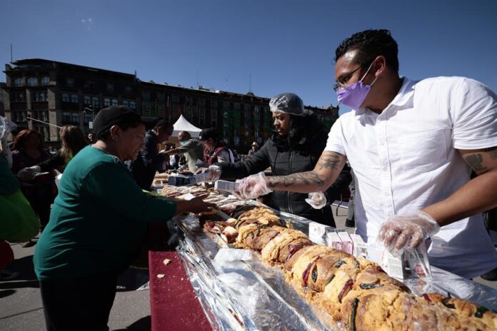 Personas reciben una porción de la tradicional Rosca de Reyes, hoy, en la explanada del Zócalo de la Ciudad de México (1) rosca de reyes