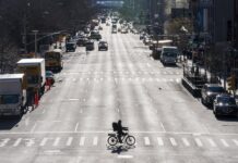 Una persona cruza hoy en bicicleta la céntrica calle Hudson en Manhattan