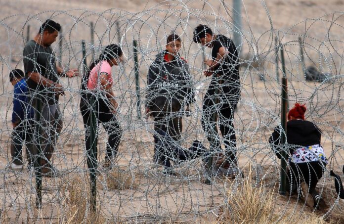 Migrantes intentan cruzar la cerca de alambres en la frontera que divide a México de los Estados Unidos (2)