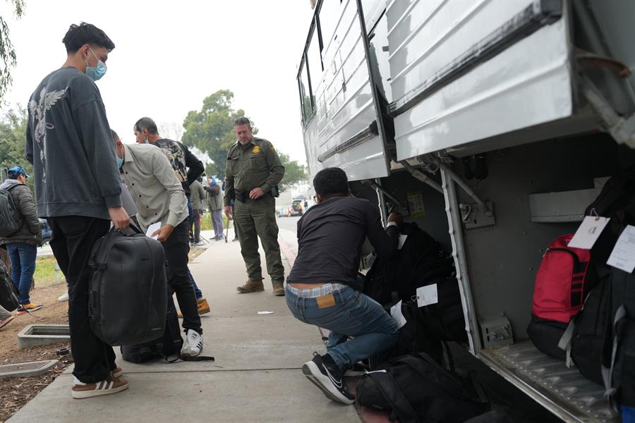 Un grupo de migrantes liberados por la Patrulla Fronteriza esperan un autobús (1)