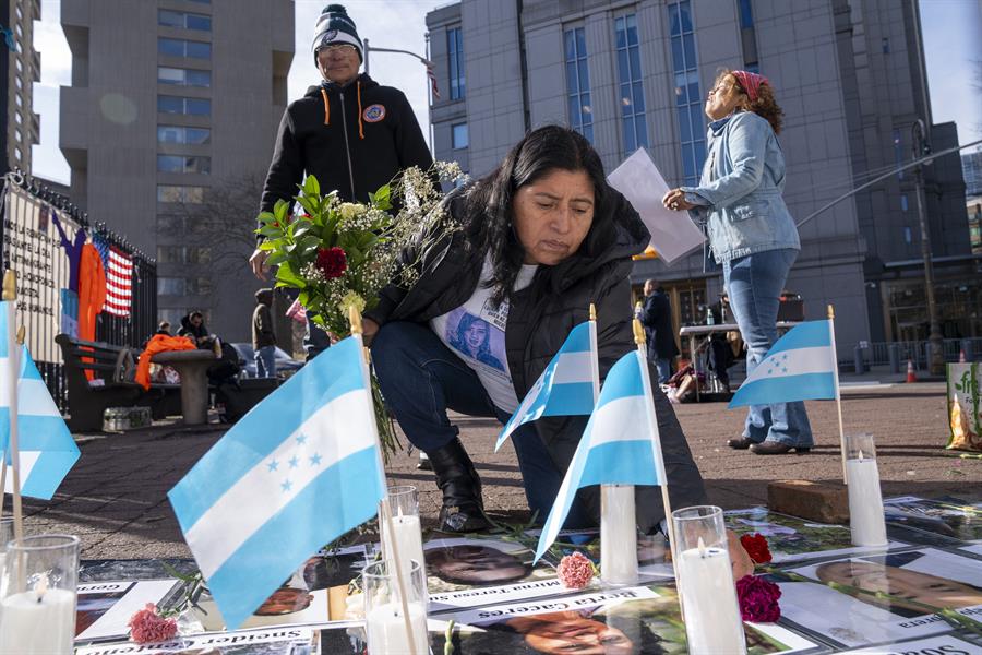 Una hondureña deposita flores y velas junto a unos carteles con las fotos de fiscales, periodistas, campesinos, estudiantes y líderes ambientalistas, víctimas del expresidente hondureño Juan Orlando Hernández, mientras esperan la sentencia del juez en contra del exmandatario.