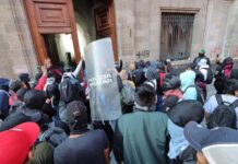 Manifestantes encapuchados vandalizan una de las puertas del Palacio Nacional este miércoles, en Ciudad de México.