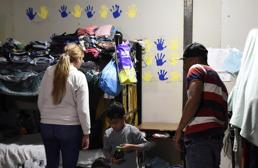 Migrantes organizan sus pertenencias en un albergue