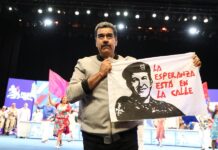 Presidente de Venezuela Nicolás Maduro sosteniendo una bandera con la imagen del fallecido presidente Hugo Chávez.