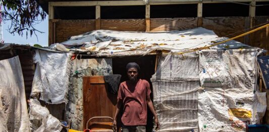 Un hombre posa en el lugar donde vive junto a su familia en el campamento de refugiados en el Liceo Marie Jeanne este jueves, en Puerto Príncipe, Haití.