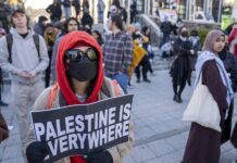 Un estudiante sostiene un cartel en una protesta universitaria propalestina