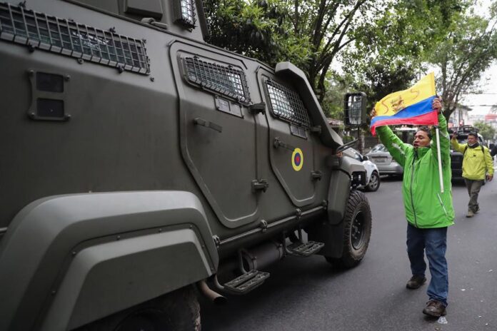 Un hombre exhibe una bandera mientras pasa un vehículo blindado donde es trasladado el exvicepresidente ecuatoriano Jorge Glas Ecuador