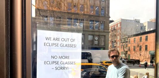 Un hombre llega a una biblioteca donde tiene colgado en la puerta un cartel que anuncia el agotamiento de las gafas para ver el elipse solar