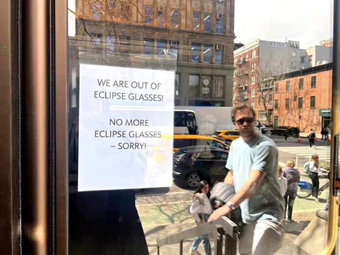 Un hombre llega a una biblioteca donde tiene colgado en la puerta un cartel que anuncia el agotamiento de las gafas para ver el elipse solar Un hombre llega a una biblioteca donde tiene colgado en la puerta un cartel que anuncia el agotamiento de las gafas para ver el elipse solar