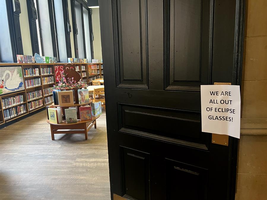 cartel colgado en la puerta de una biblioteca donde se anuncia que se quedaron sin gafas para ver el eclipse solar