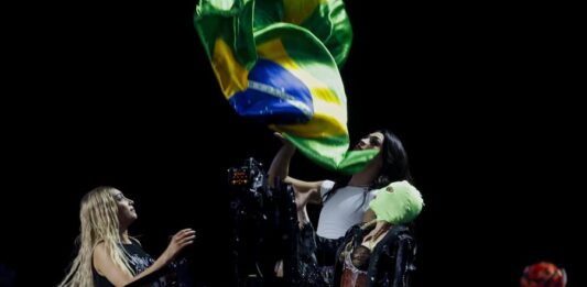 La cantante estadounidense Madonna (d) y la cantante brasileña Pablo Vittar (c) lanzan banderas de Brasil