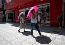 Mujeres sostienen sombrillas para protegerse del so