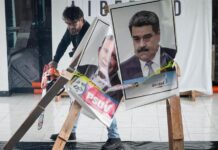Un candidato presidencial corta con una motosierra afiches de Maduro y de González Urrutia
