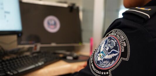 Un agente de la Oficina de Aduanas y Protección Fronteriza de Estados Unidos (CBP) mira desde su ventanilla a los inmigrantes q