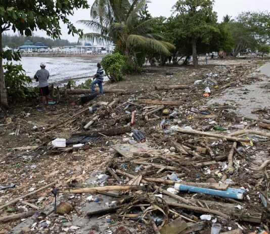 Hombres observan uno de los muelles destruidos en la Marina ZarPar, tras el paso del huracán Beryl