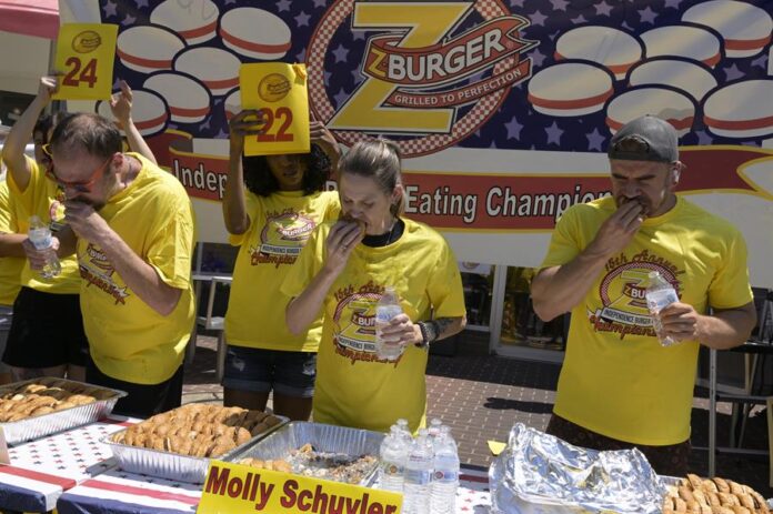 Los concursantes Dan 'Killer' Kennedy (i), Molly Schuyler (c), y Joel Hansen participan de la 15 edición del concurso anual de comer hamburguesas