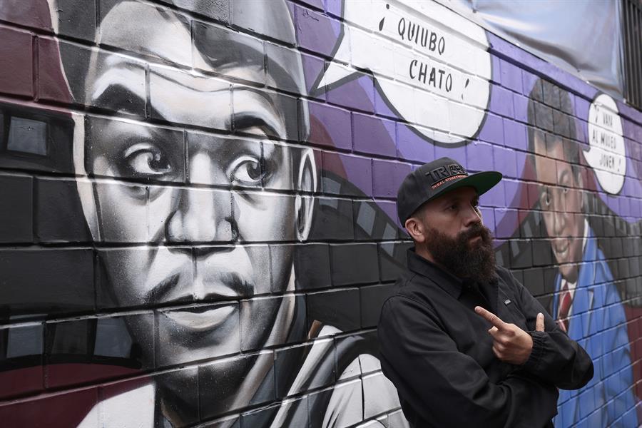 El artista urbano Yuka posa junto a su mural dedicado al actor mexicano Mario Moreno Cantinflas,
