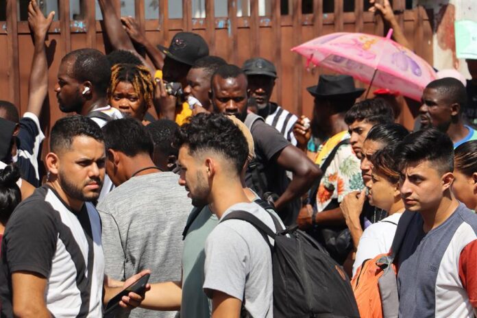 Migrantes hacen fila a la esperar de resolver su situación migratoria Migrantes
