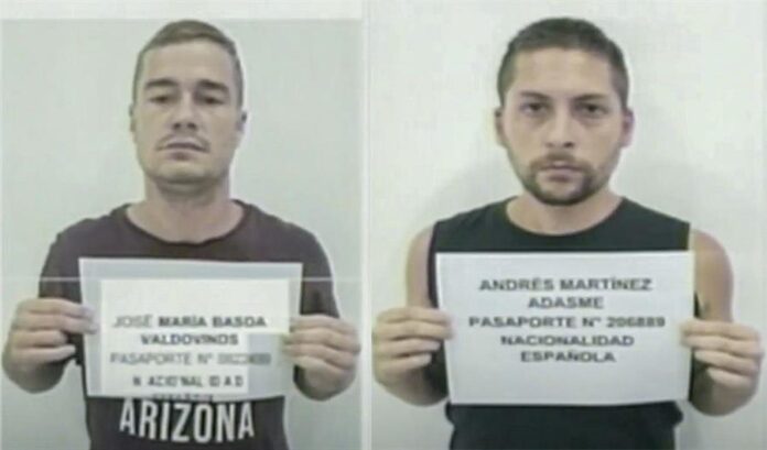los ciudadanos españoles José María Basoa(i) y Andrés Martínez Adasne (d) sosteniendo una hoja con sus datos de identificación, en Caracas