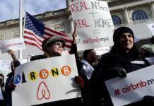 personas sosteniendo carteles a favor de las operaciones de la empresa Airbnb