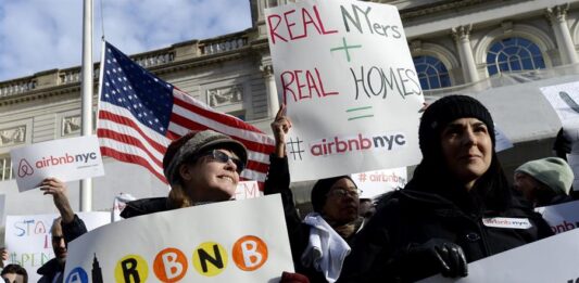personas sosteniendo carteles a favor de las operaciones de la empresa Airbnb