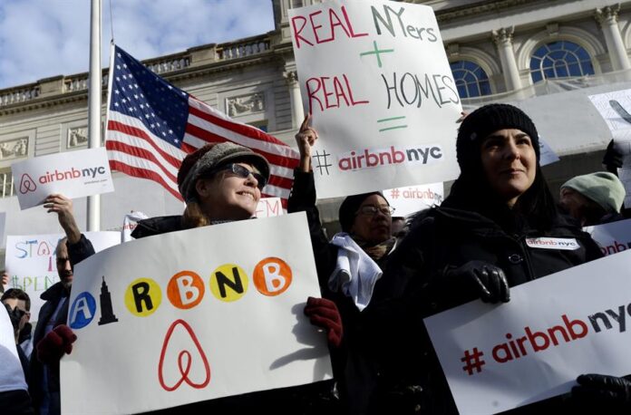 personas sosteniendo carteles a favor de las operaciones de la empresa Airbnb personas sosteniendo carteles a favor de las operaciones de la empresa Airbnb