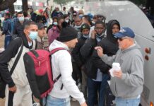 Robert Vivar (d), de la Iglesia Episcopal de San Diego, hablando con un grupo de migrantes